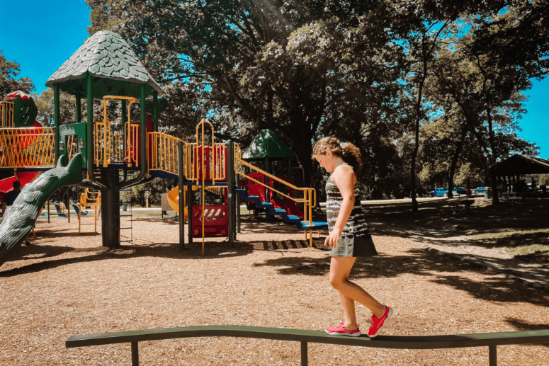Girl Walking On Balance Beam At A Park