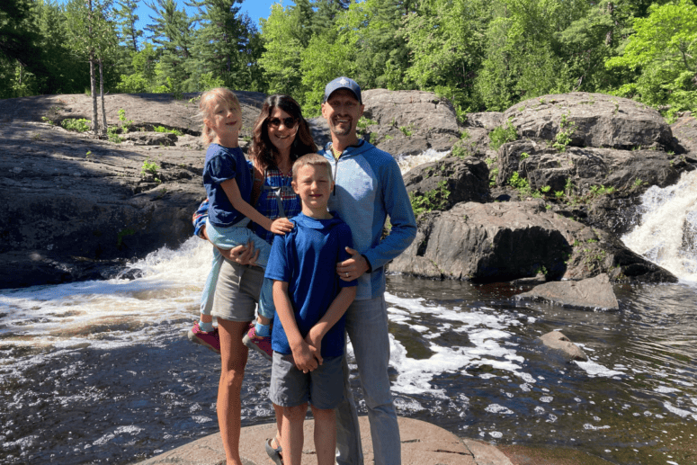 A Family Gathered At The Base Of A Waterfall.