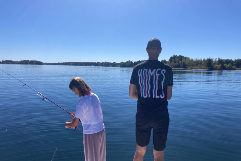 A Girl And A Man Fishing On The Back Of A Boat.